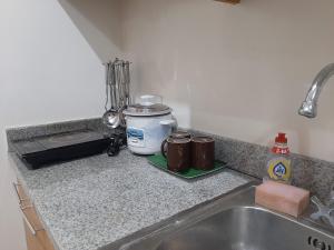 a kitchen counter with a sink and two coffee mugs at Family Staycation 2 with Pool in Manila