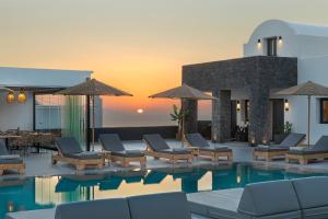 a resort pool with lounge chairs and a sunset at Onyx Hotel & Suites in Karterados