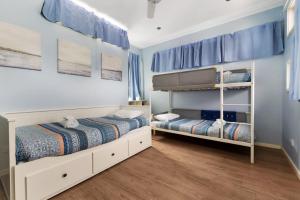 two beds in a bedroom with blue walls and wooden floors at Orion Blue Beach Stay Vincentia in Vincentia