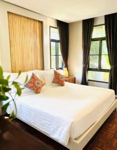 1 dormitorio con 1 cama blanca grande y 2 almohadas en Sirarun Resort, en Ban Krut