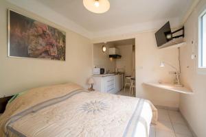 a small bedroom with a bed and a kitchen at Le figuier air-conditioned studio and swimmin in Marseille