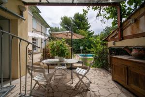 une terrasse avec une table, des chaises et un parasol dans l'établissement Le figuier air-conditioned studio and swimmin, à Marseille