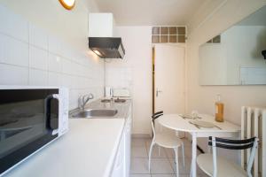 Le figuier air-conditioned studio and swimmin في مارسيليا: مطبخ مع حوض وطاولة مع كراسي