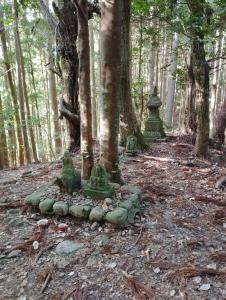 un grupo de estatuas verdes en medio de un bosque en Kumano Kodo Nagano Guesthouse en Tanabe