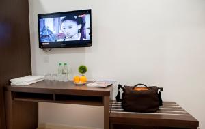 a room with a television on a wall with a bench at Big Orange Hotel Sungai Petani in Sungai Petani