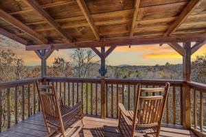 two rocking chairs sitting on a porch with a sunset at Five-Bedroom House in Sevierville