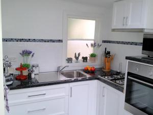 a kitchen with white cabinets and a sink and a window at Devon Long Barn in Bowral