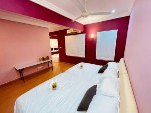 1 cama blanca grande en una habitación con paredes rojas en Trendy Family Getaway by StayCo - Mini-Pool, Outdoor Cinema, Air Loft, PS4, KTV - Just 2 mins to Beach! en Batu Ferringhi
