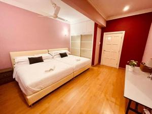 a large white bed in a room with red walls at Trendy Family Getaway by StayCo - Mini-Pool, Outdoor Cinema, Air Loft, PS4, KTV - Just 2 mins to Beach! in Batu Ferringhi