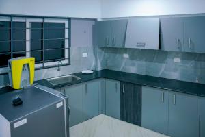 a kitchen with blue cabinets and a yellow chair at EMFORE ELANZA in Kottayam