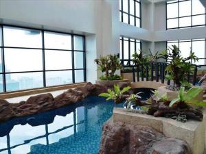 a swimming pool in a building with a rock wall at Posh Beds with City View and Pools in Manila