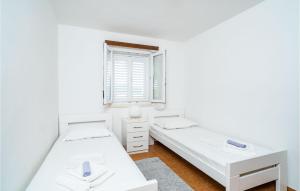 two beds in a white room with a window at Gorgeous Home In Slano With House Sea View in Slano