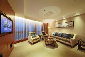 a living room with a couch and chairs and a tv at Shenzhen Nanshan L'Hermitage in Shenzhen