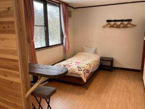 a bedroom with a bed and a desk and a window at Piremon in Hakuba