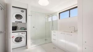 une salle de bain blanche avec une machine à laver et un lavabo dans l'établissement Edgecliffe Unit 10 Kings Beach QLD, à Caloundra