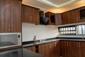 eine Küche mit Holzschränken und einer Mikrowelle in der Unterkunft MercuryIcon luxury Homes in Abuja