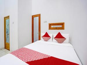- un lit blanc avec des oreillers rouges et blancs dans l'établissement OYO Life 92030 Ef Palm Guest House Family, à Surabaya
