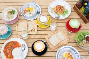 a table with plates of food and cups of coffee at Grow home -Stay and space, Self check-in in Chiang Rai