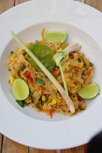 a white plate of food with noodles and lime slices at The High Dive Gili Gede by Ultimate Resorts in Gili Gede