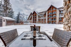 una mesa con una botella de vino en un patio cubierto de nieve en Mountain Retreat, Pool & Hot Tub, BBQ, Patio, King Bed, Sleeps 6!, en Canmore