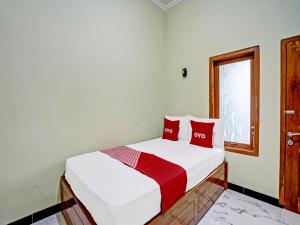 a bedroom with a bed with red pillows and a window at OYO Life 92043 Kost Barokah Syariah Madiun in Madiun