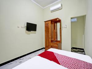- une chambre avec un lit et une télévision murale dans l'établissement OYO Life 92043 Kost Barokah Syariah Madiun, à Madiun