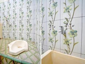 La salle de bains est pourvue de toilettes et de fleurs sur le mur. dans l'établissement OYO Life 92043 Kost Barokah Syariah Madiun, à Madiun