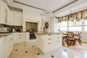 cocina con armarios blancos, mesa y sillas en Luxury Villa Pool and Spa, en Magdalenka