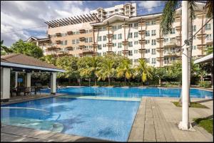 a hotel with a large swimming pool in front of a building at A Refreshing Condo Unit Near BGC, Ortigas & Makati with NETFLIX and WiFi in Manila