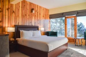 a bedroom with a bed and a large window at Gali's End By Roomy, Kalabagh Nathiagali in Nathia Gali