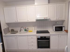 a kitchen with white cabinets and a sink and a microwave at Luxury Apartments Mascarat in Altea