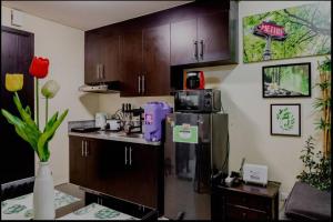 een keuken met houten kasten en een koelkast bij A Refreshing Condo Unit Near BGC, Ortigas & Makati with NETFLIX and WiFi in Manilla