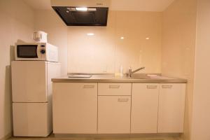 W kuchni znajduje się biała lodówka i kuchenka mikrofalowa. w obiekcie SEVEN Building / Vacation STAY 4946 w mieście Asahikawa