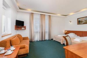 a hotel room with a couch and a table at Hotel Artur in Kraków