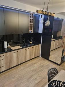 a kitchen with wooden cabinets and black counters at Apartament Loft KB-Ściegiennego (garaż, centrum) in Kielce