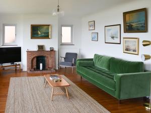 a living room with a green couch and a fireplace at Seaways in Lee-on-the-Solent