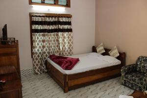 a small bedroom with a bed and a chair at Green Reed Resort By Meenakshi, Kaziranga in Hatikhuli