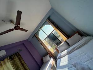 1 dormitorio con ventilador de techo y ventana en Three Angels Lodge & Restaurant, en Chitwan