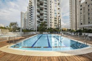 een groot zwembad met hoge gebouwen op de achtergrond bij Luxury 2 BR Apt w Pool & Panoramic View by Sea N' Rent in Tel Aviv