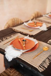 a wooden table with orange plates and gold utensils at The Oasis Bali in Canggu