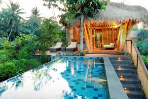 a resort with a swimming pool and a hut at Fivelements Retreat Bali in Ubud