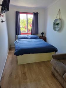 1 dormitorio con cama con sábanas azules y ventana en Beachside Backpackers en Port Macquarie