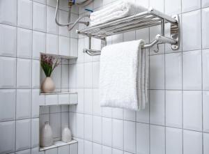 a bathroom with white tiled walls and a towel rack at Fred and Winnie BnB in Kampala