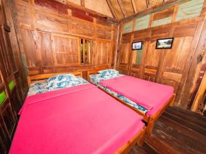 a room with two beds in a wooden cabin at Villa Kampung Ayem Riverside in Sleman