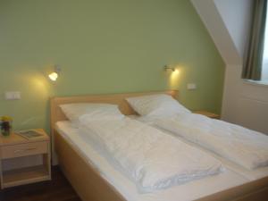 1 cama con sábanas blancas y almohadas en una habitación en Stadthotel Bocholt, en Bocholt