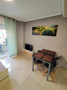 un soggiorno con tavolo, sedie e TV di Apartament Goleta a Torrevieja