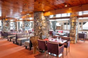 a restaurant with tables and chairs and a stone wall at Hôtel L'Aiguille Percée in Tignes