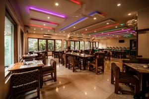 a restaurant with wooden tables and chairs and purple lights at Aranya Nivas in Thekkady