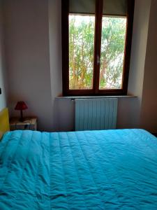 a bedroom with a blue bed and a window at Casa Lucia in Rosignano Solvay