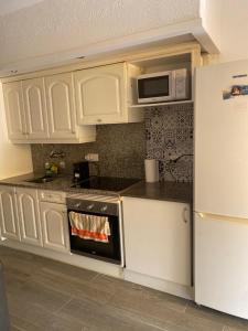 a kitchen with white cabinets and a stove and a microwave at Apartamento alto standing con piscina privada, aire acondicionado y wifi in Platja d'Aro